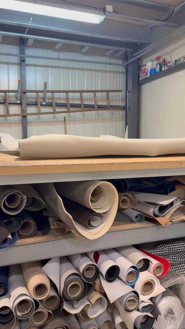 Rouleaux de tissus de garniture rangés sur les étagères de l’atelier