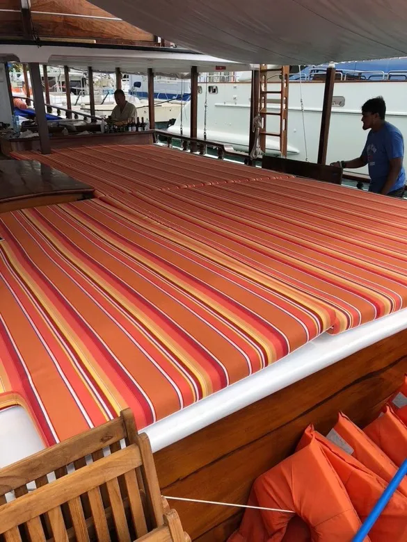 Bain de soleil en toile rayée sur le pont d’un bateau en bois verni