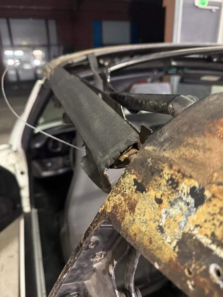 Armature de capote de Porsche 911 rongée par la rouille et couverte de colle ancienne, avant nettoyage