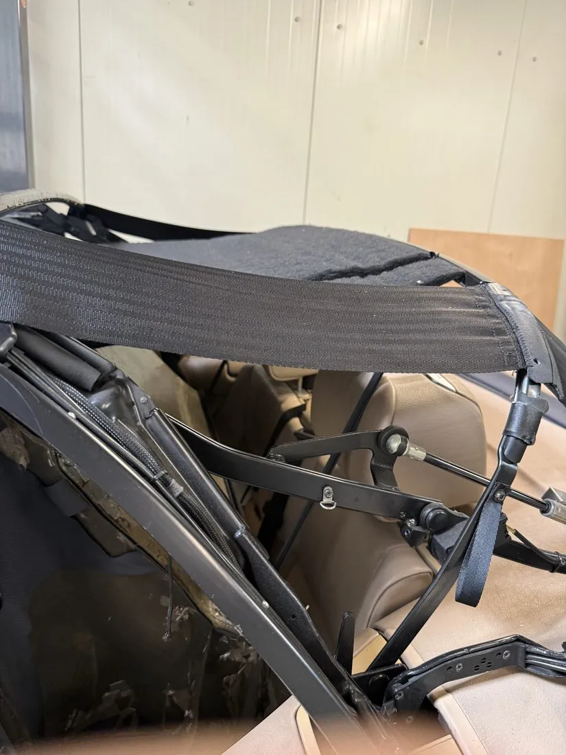 Armature de capote de cabriolet déposée, sangles de tension noires visibles au-dessus de l’habitacle beige