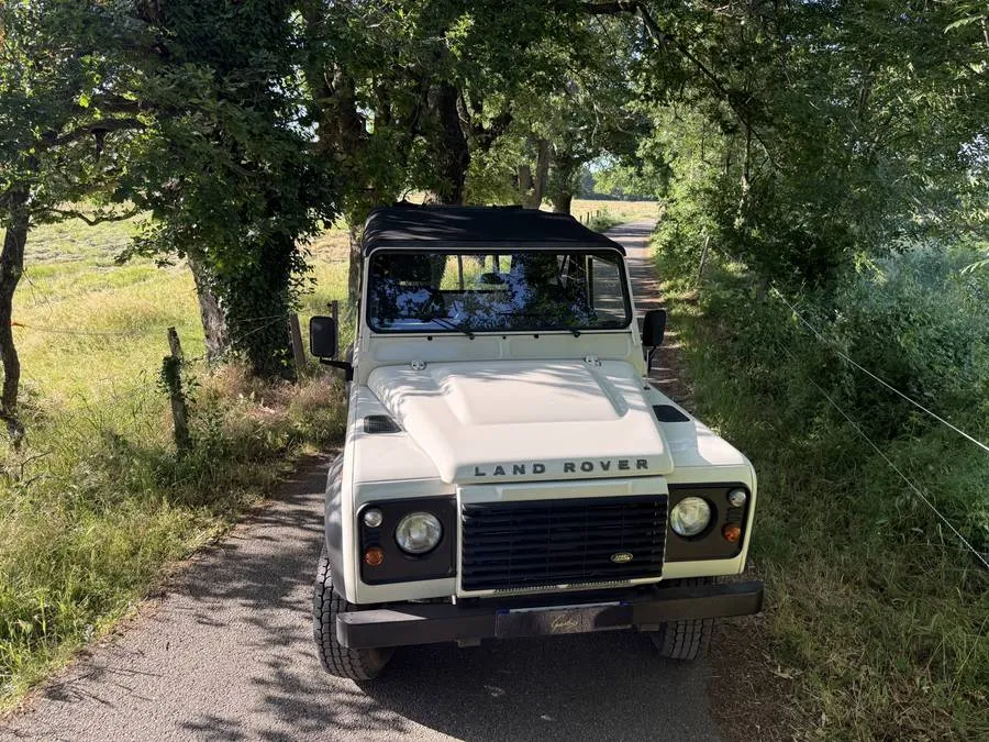 Land Rover Defender blanc vu de face avec sa capote noire sur mesure posée