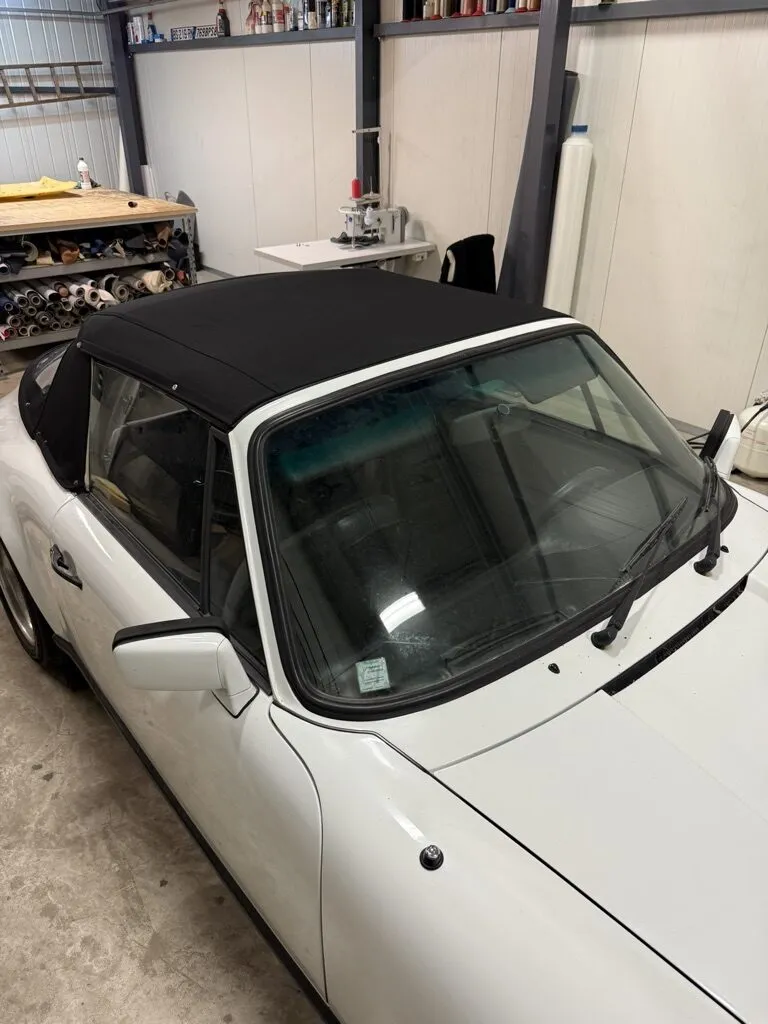 Porsche 911 SC cabriolet blanche avec sa capote neuve posée et fermée dans l’atelier