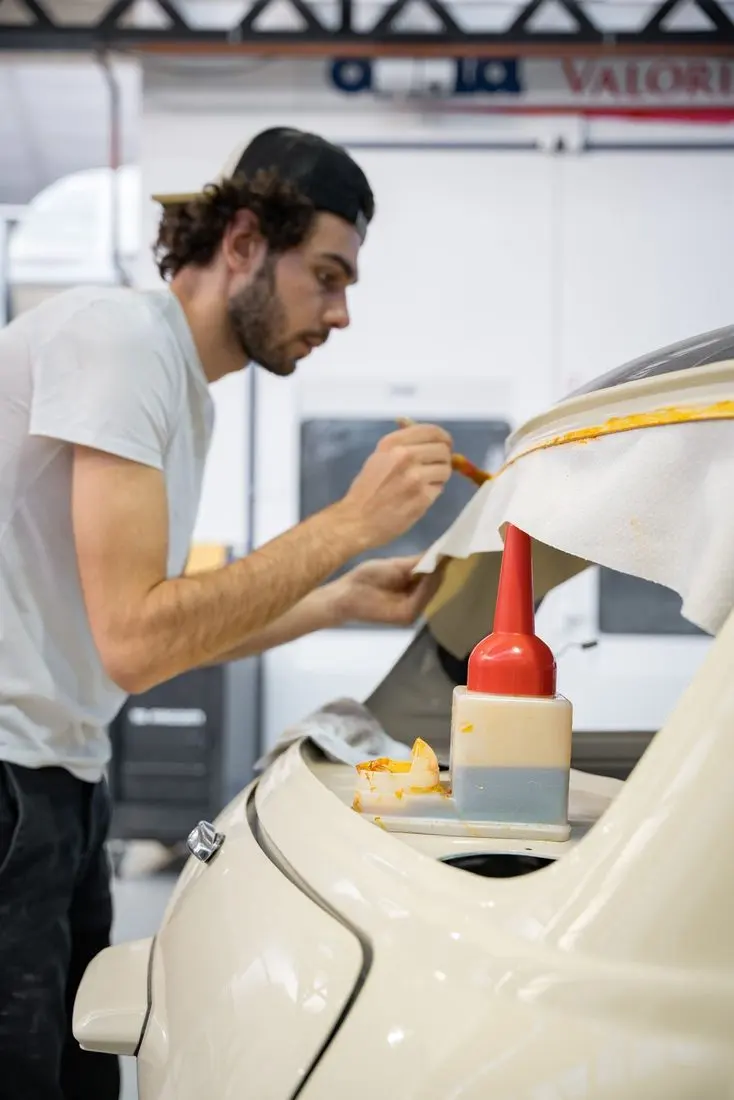 Charles Bailly encollant à la brosse la coque d'un véhicule dans son atelier de Chaponost