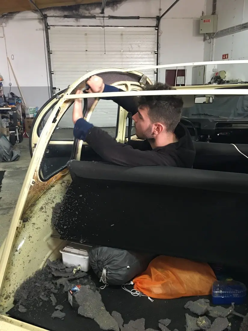 Charles Bailly déposant la capote usée d'un cabriolet ancien avant de poser la toile neuve
