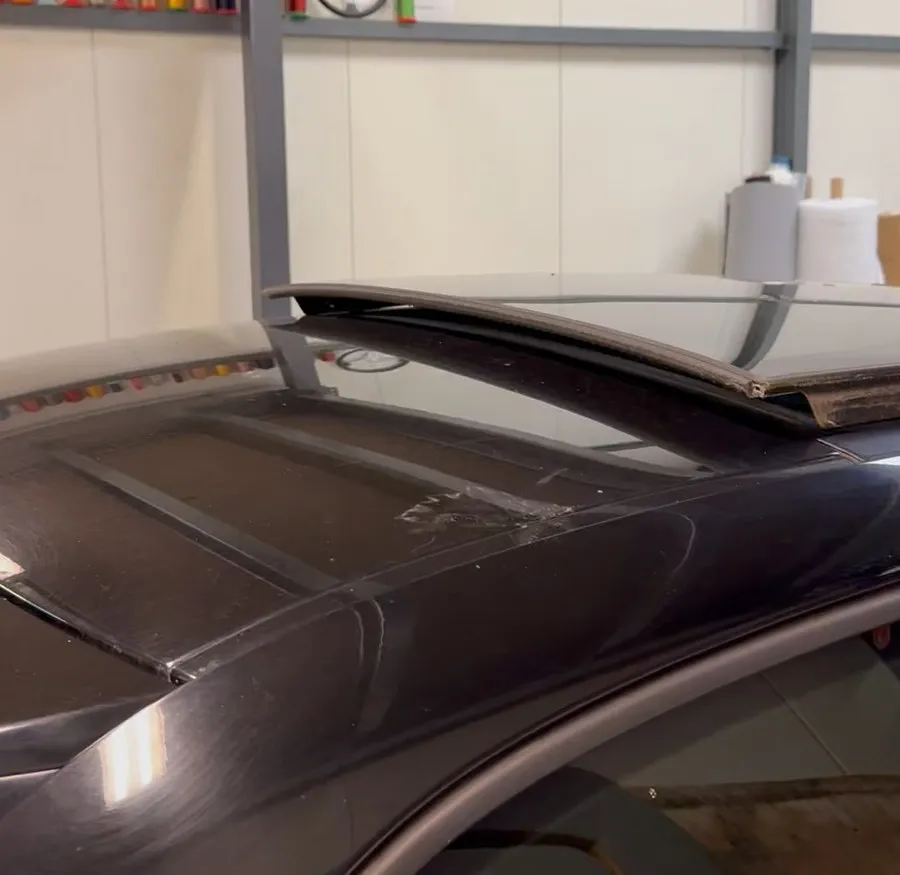 Vitrage du toit ouvrant d’une Audi A1 noire soulevé de son logement dans l’atelier