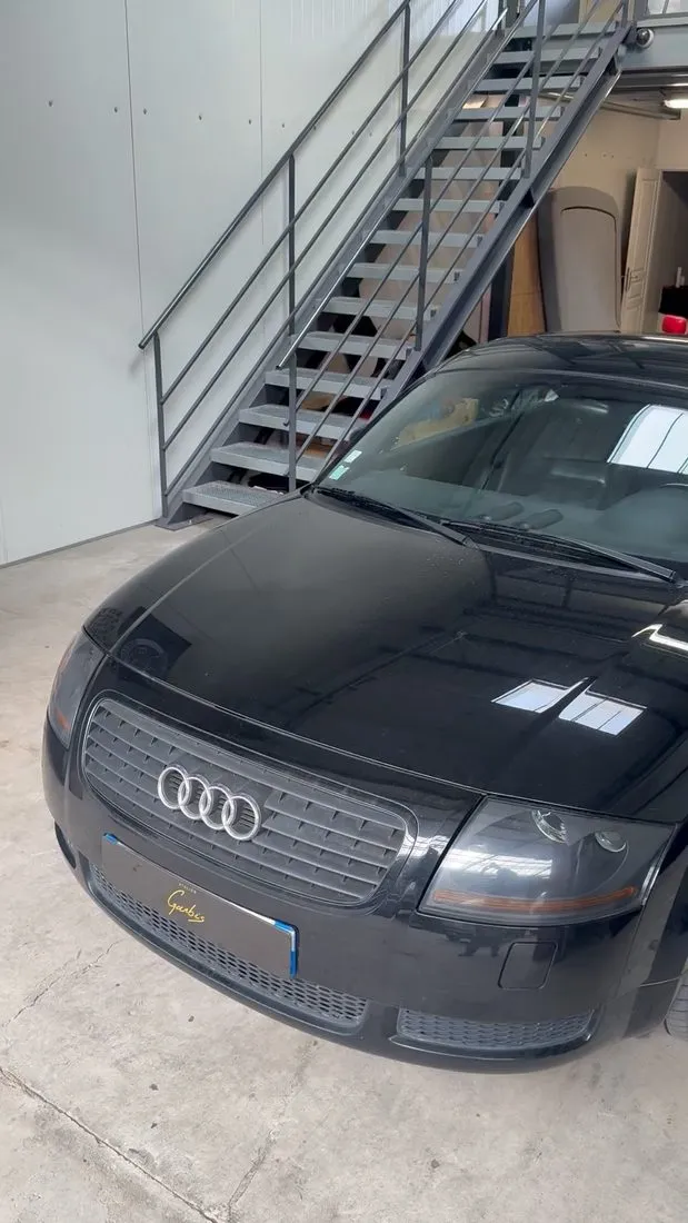 Audi TT noire garée dans l’atelier avant la dépose du ciel de toit