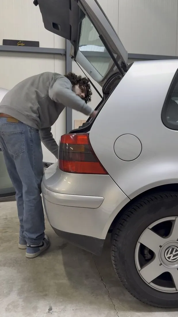 Dépose de la coque de ciel de toit par le hayon ouvert d’une Volkswagen Golf 4 grise