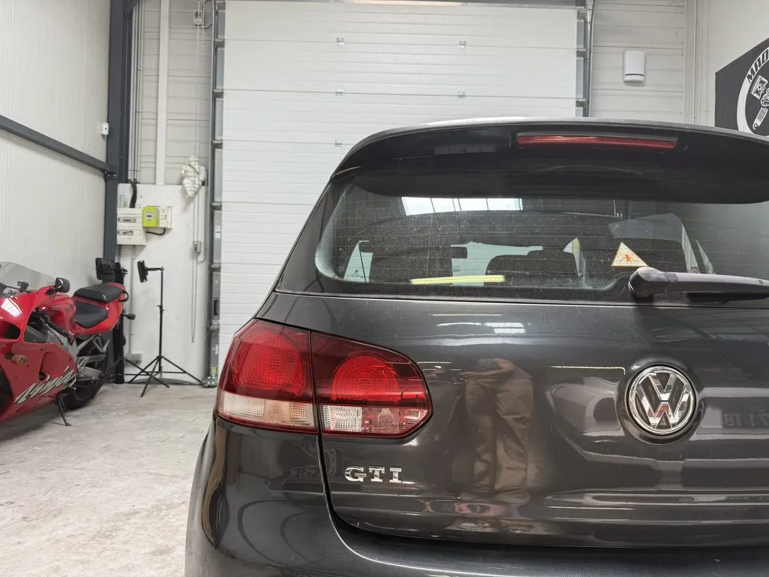 Volkswagen Golf GTI grise garée dans l’atelier, vue de trois quarts arrière