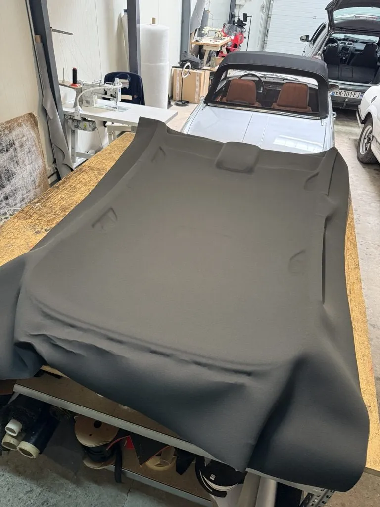 Tissu de garniture neuf posé sur la coque de ciel de toit d’une Golf GTI dans l’atelier