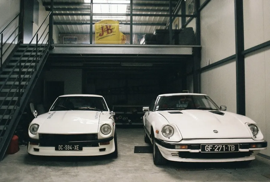 Deux Datsun blanches garées dans l’atelier, la 280 ZX de ce chantier à droite