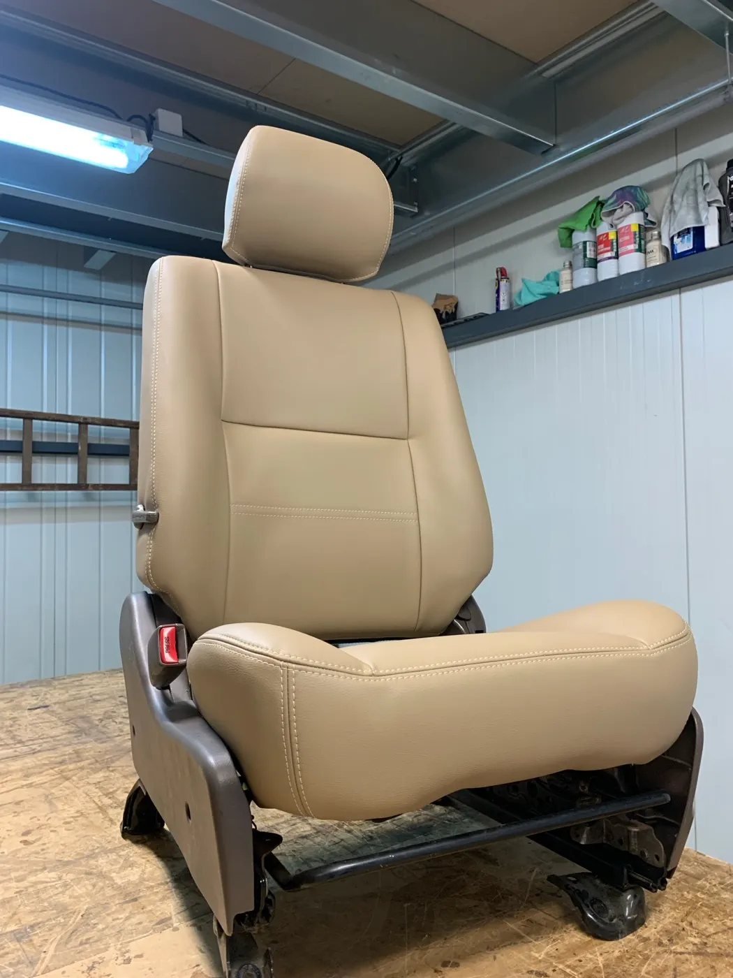Siège de Toyota Land Cruiser regarni en simili beige, posé seul sur l’établi de l’atelier