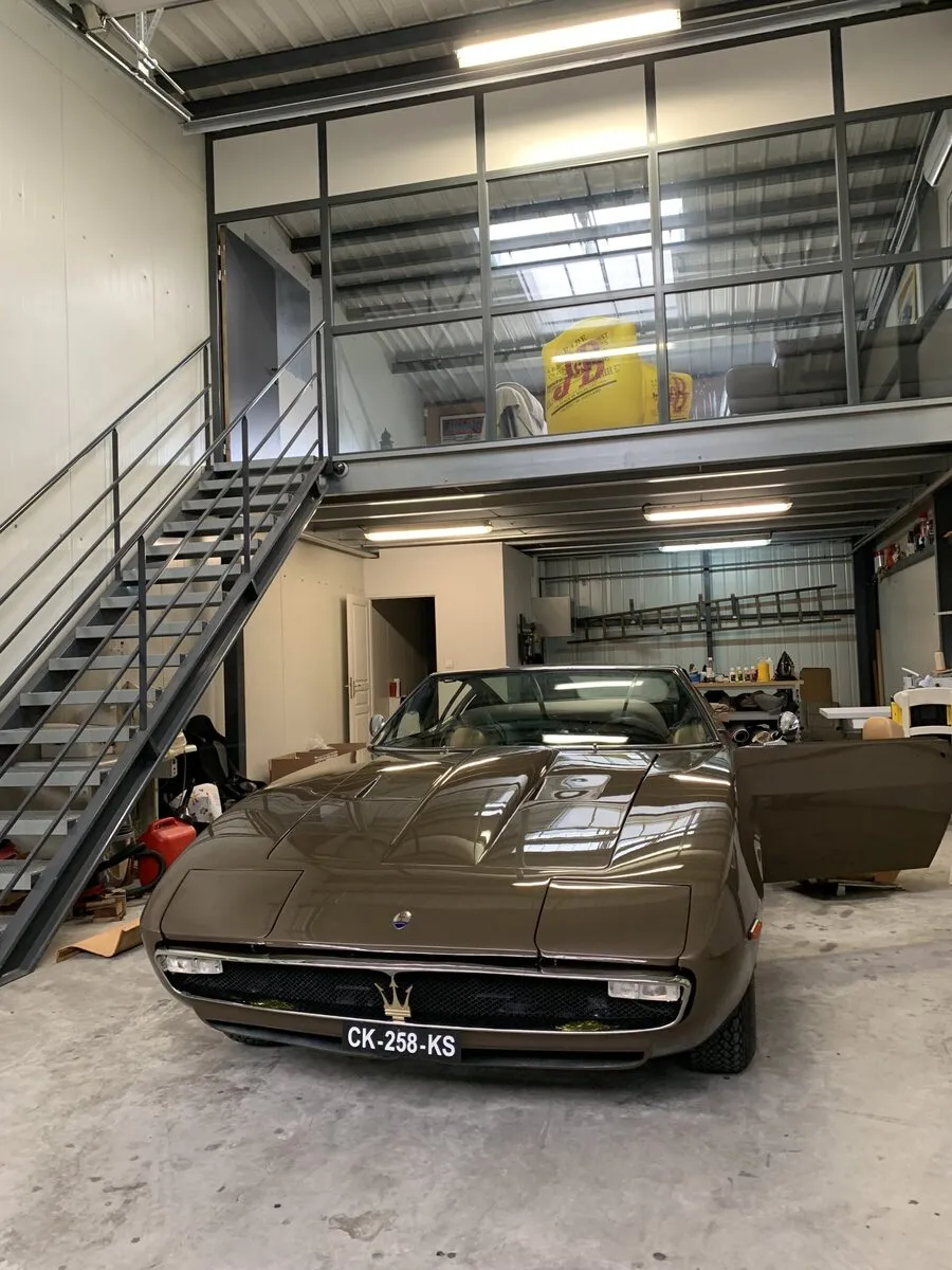 Maserati Ghibli bronze garée dans l’atelier de Chaponost, sous la mezzanine