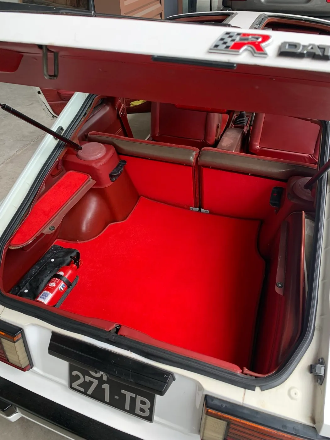 Coffre de Datsun 280 ZX avec sa moquette rouge sur mesure posée, hayon ouvert et dossiers arrière rabattus