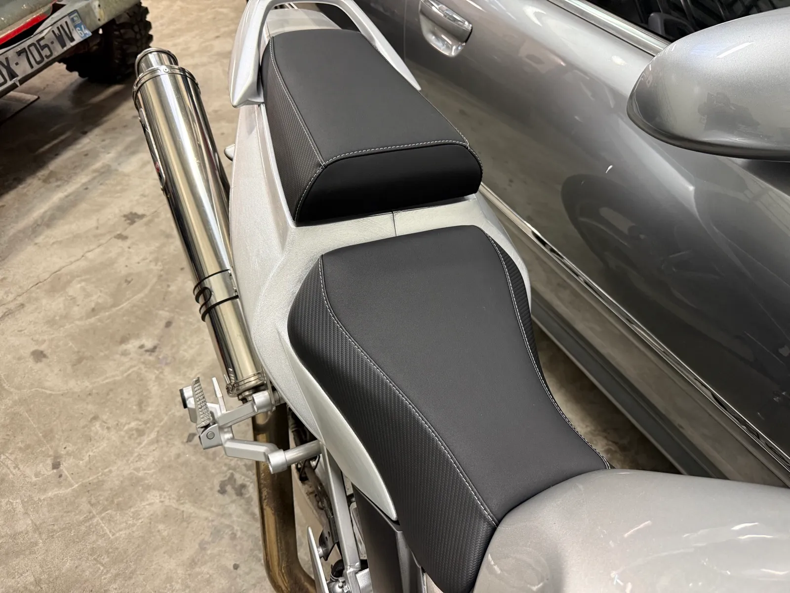 Selle de Suzuki SV 650 refaite en simili noir mat, flancs carbone et surpiqûres blanches, remontée sur la moto