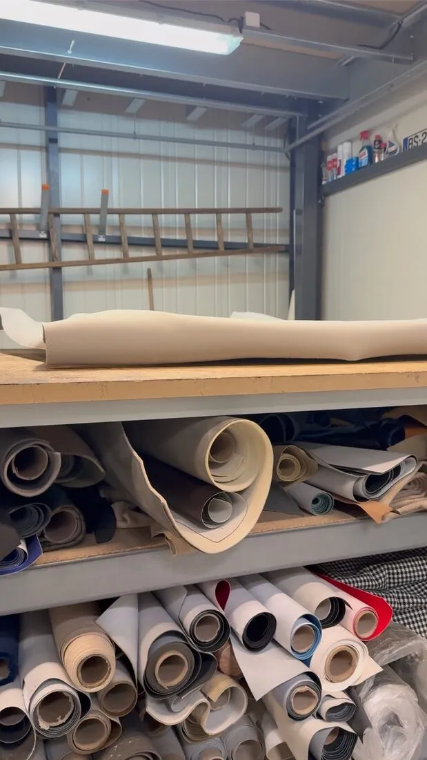 Rouleaux de tissus et de cuirs rangés dans l’atelier, le stock d’échantillons de sellerie