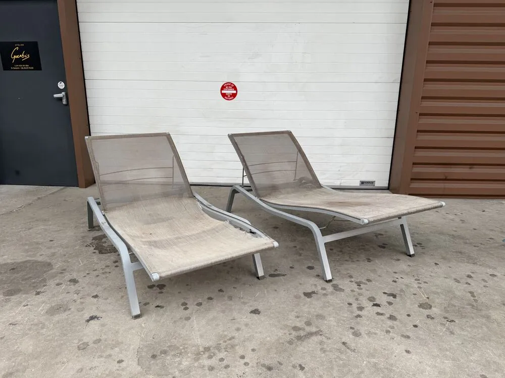 Deux transats à toile beige détendue et salie, avant réfection, devant l’atelier
