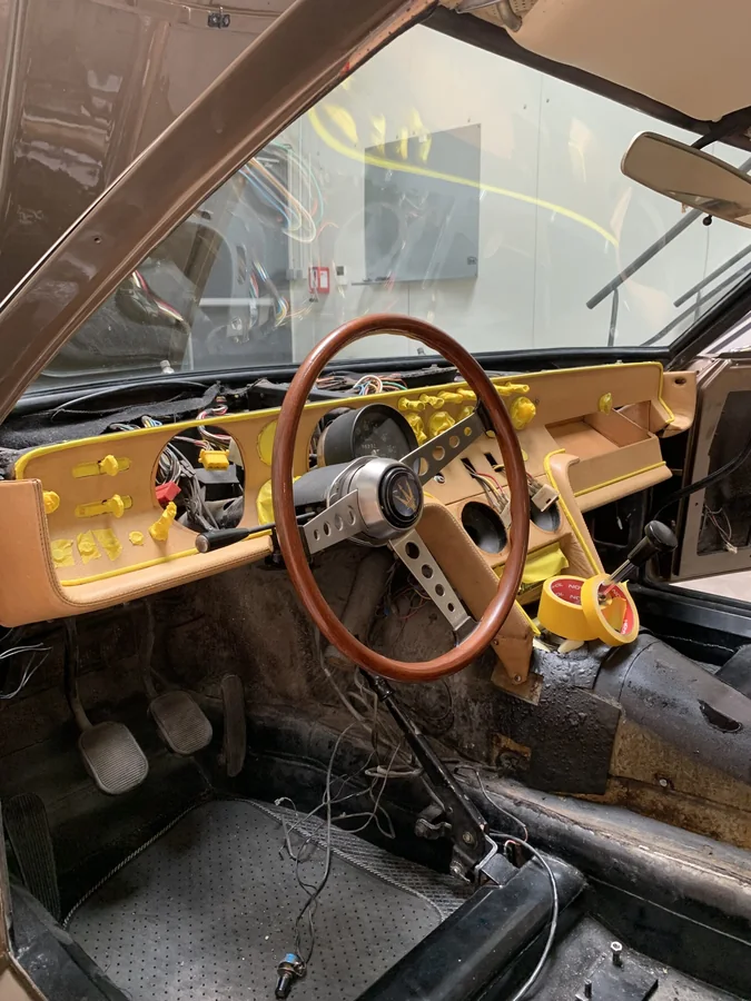 Habitacle de Maserati Ghibli en cours de chantier, plancher nu, sièges déposés et instruments protégés au ruban de masquage